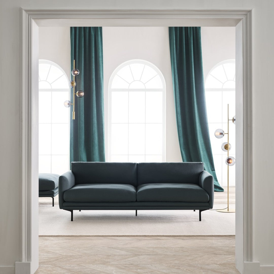 Modern black sofa with sleek lines, complemented by rich teal curtains and a neutral beige floor.