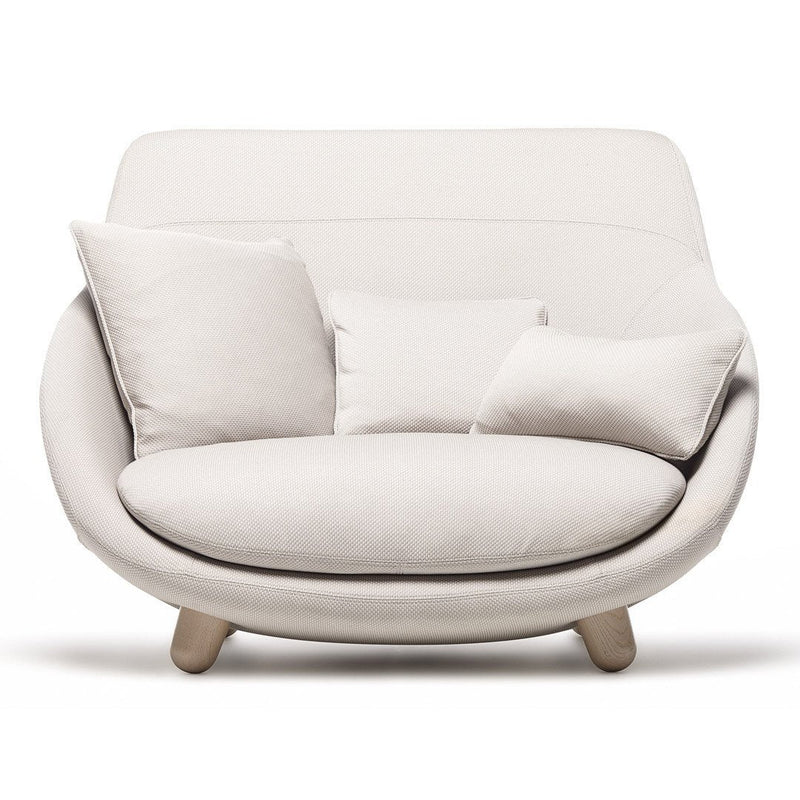 Cream-colored curved sofa with soft fabric and plush pillows, paired with light wood legs for a modern look.