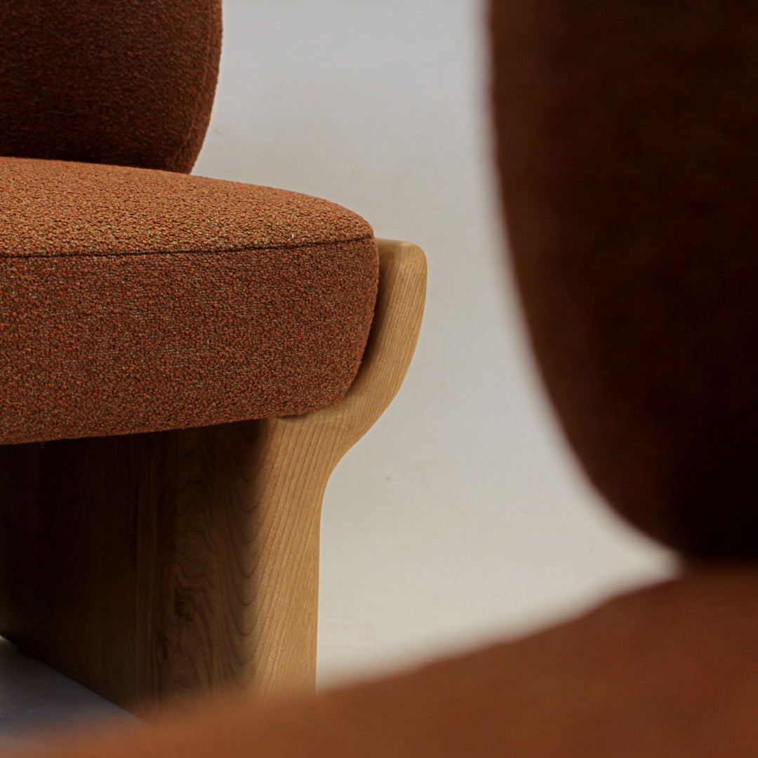 Warm orange fabric texture with subtle flecks, complemented by natural wooden accents. Modern and inviting design.