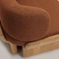 Rust orange textured upholstery with a rounded armrest, complemented by a light wood base.
