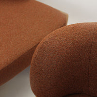 Warm orange textured fabric from a modern chair and cushion, featuring a subtle heather pattern. Perfect for cozy interiors.