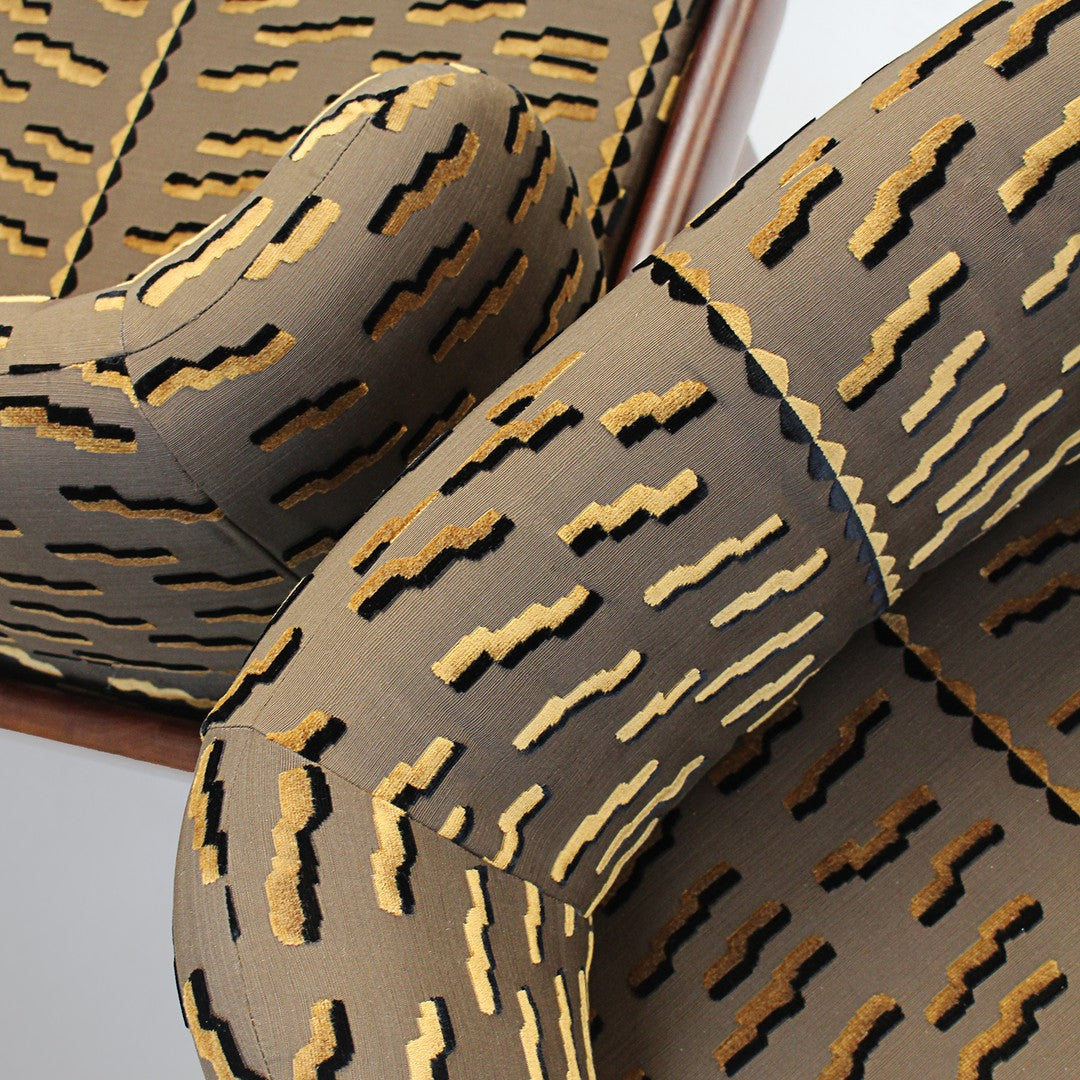 Tan and black abstract pattern with golden accents on upholstered fabric, perfect for modern decor.