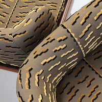 Tan and black abstract pattern with golden accents on upholstered fabric, perfect for modern decor.