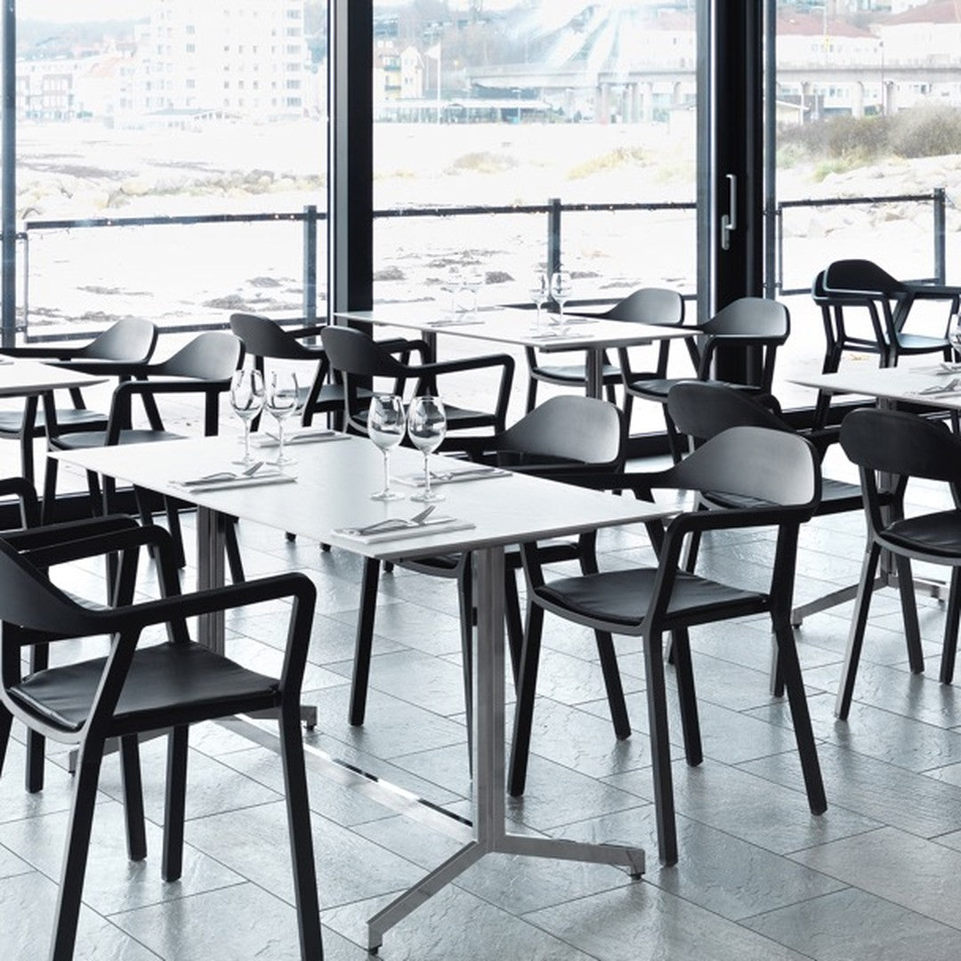 Modern dining set with sleek black chairs and white tabletops in a minimalist setting with a coastal view.