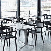 Modern dining set with sleek black chairs and white tabletops in a minimalist setting with a coastal view.