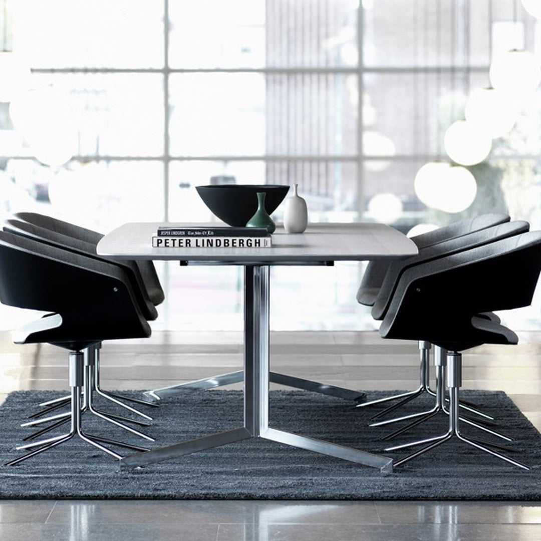 Modern dining set with sleek black chairs, gray tabletop, and dark gray rug, featuring minimalist design elements.