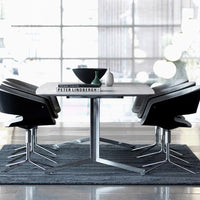 Modern dining set with sleek black chairs, gray tabletop, and dark gray rug, featuring minimalist design elements.