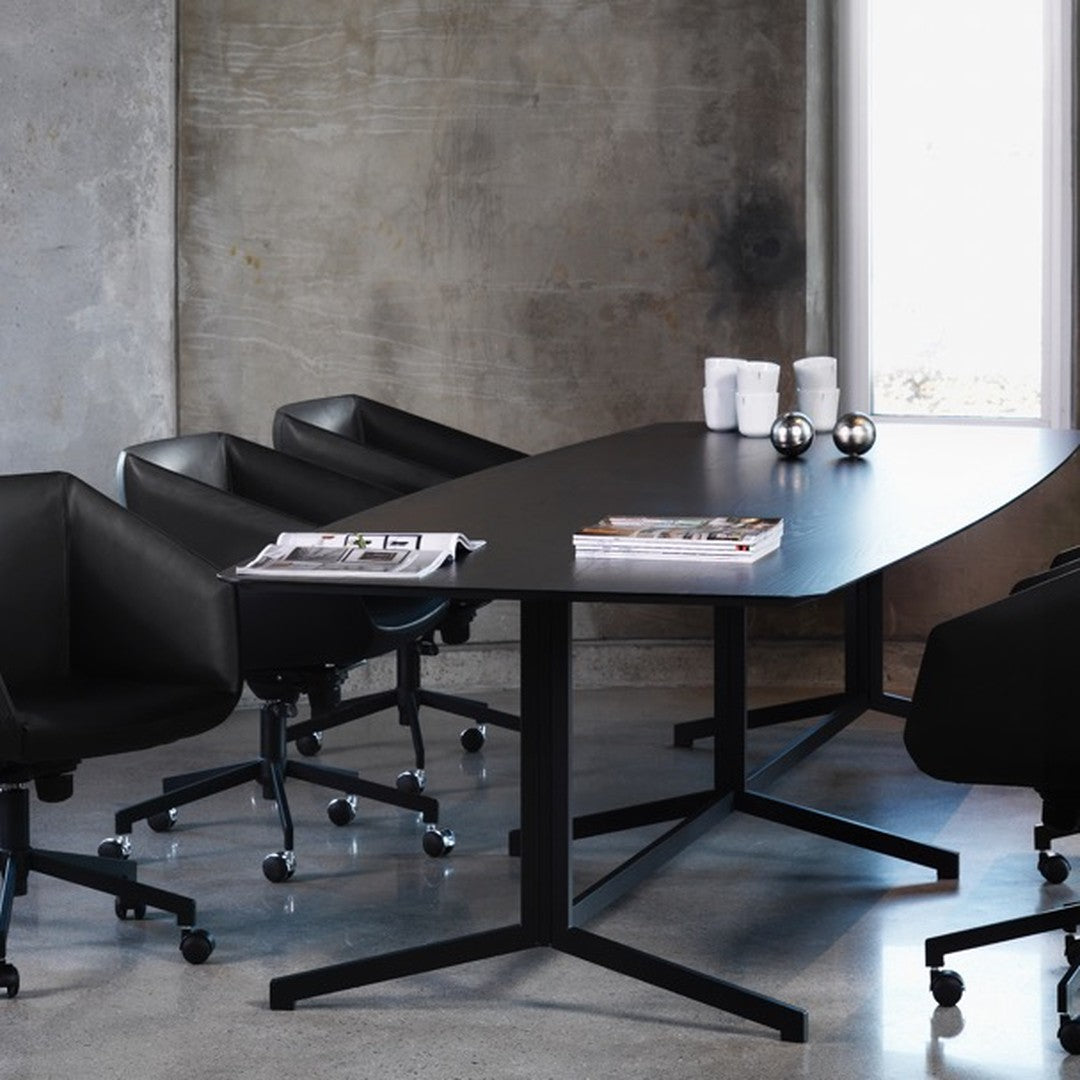 Black conference table with sleek lines and modern black chairs against a concrete wall and polished gray floor.