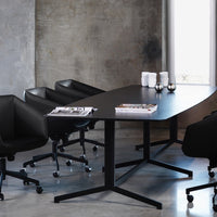 Black conference table with sleek lines and modern black chairs against a concrete wall and polished gray floor.