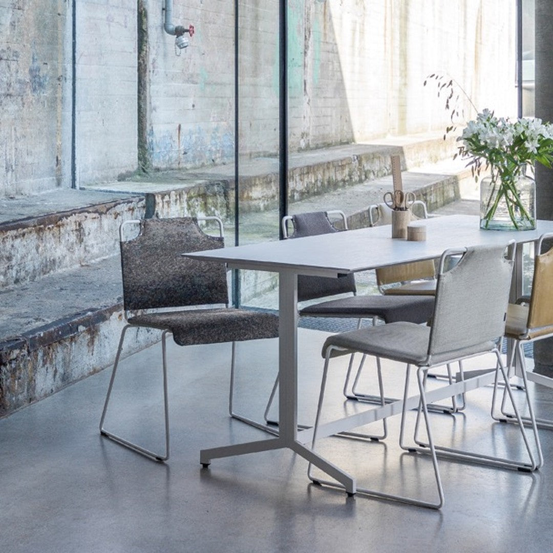 Modern dining set featuring gray, beige, and textured patterns on sleek chairs, set against a minimalist glass backdrop.