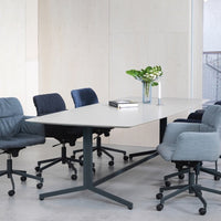 Modern office setting featuring a light gray table and upholstered chairs in varying shades of blue and gray.