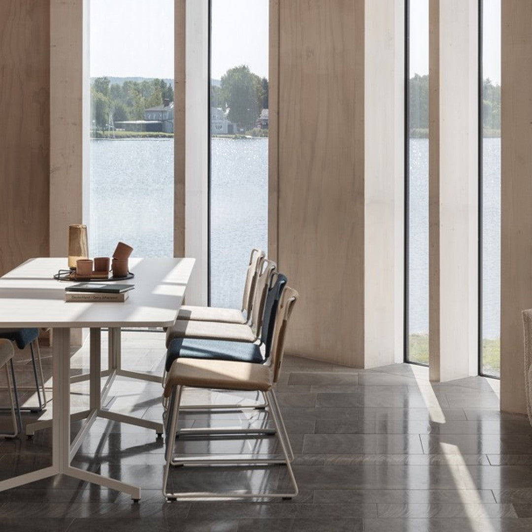 Neutral-toned chairs with blue and beige accents, stylish modern furniture in a serene, light-filled environment.