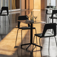 Modern black dining chairs around a minimalist black table, with warm golden light reflecting on polished gray tiles.