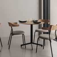 Modern wooden table with black legs, accompanied by light gray upholstered chairs and black tableware.