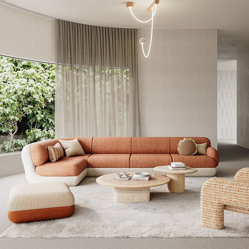 "Modern living room with an orange and cream sectional sofa, beige pouf, light wood tables, and soft textures."
