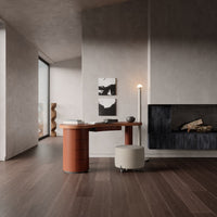 Stylish modern desk in terracotta with creamy stool, set against neutral gray walls and dark wooden flooring.