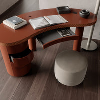Stylish curved desk in terracotta with contrasting light gray storage pouf on a dark wood floor. Modern design aesthetics.