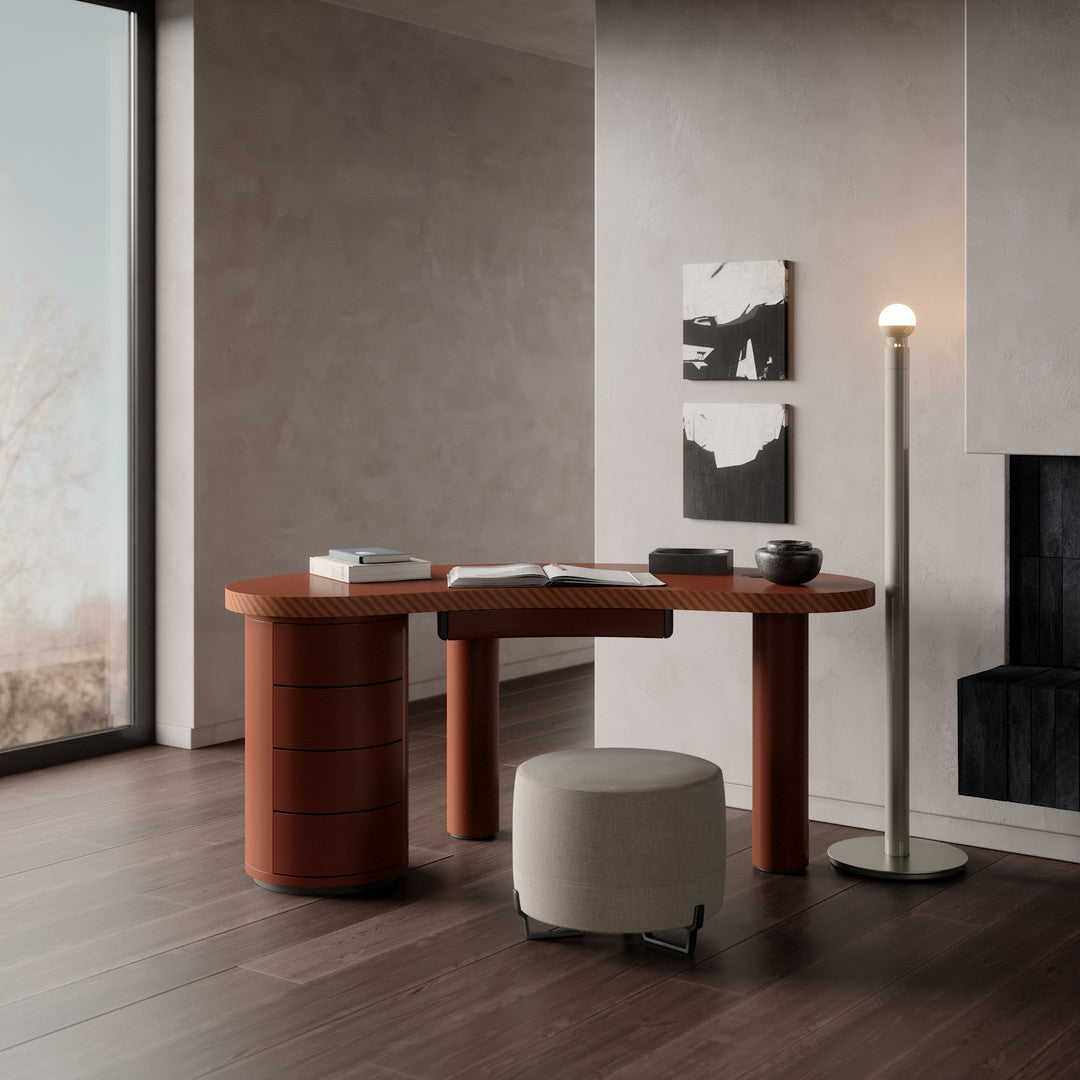 Modern desk in warm terracotta with rounded edges, paired with a minimalist gray stool and dark wooden flooring.
