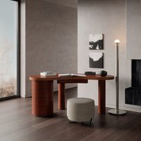 Modern desk in warm terracotta with rounded edges, paired with a minimalist gray stool and dark wooden flooring.