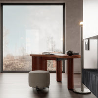 Natural wood desk in warm orange hues with a soft gray ottoman, set against a minimalist backdrop.