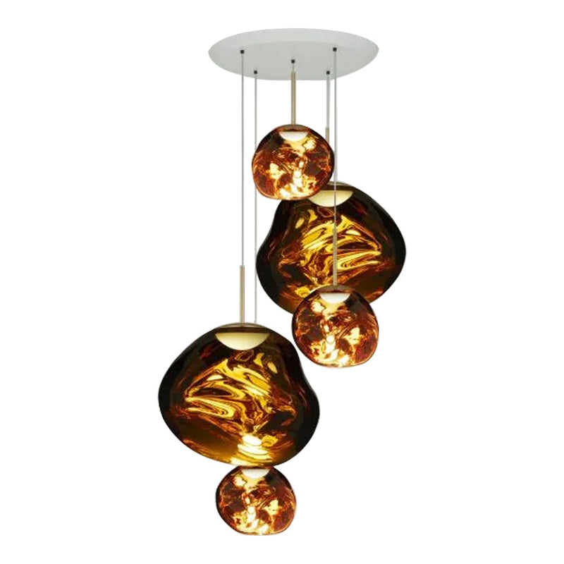 Amber glass pendant lights with organic shapes and glossy finishes hanging from a sleek white ceiling fixture.