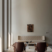 Modern beige tufted sofa, brown leather chairs, soft cream walls, and abstract wall art create an elegant, minimalist vibe.
