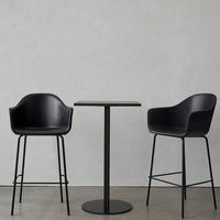Modern black bar stools with sleek design paired with a minimalist black table on a concrete floor.