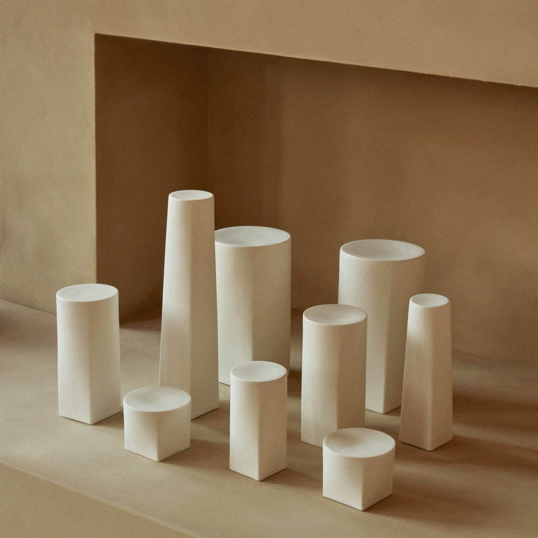 Assorted white ceramic vases in varying shapes and sizes against a soft beige background. Elegant, minimalist design.