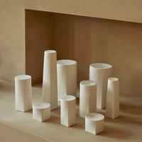 Minimalist white vases in various geometric shapes, arranged on a soft beige background. Perfect for modern decor.