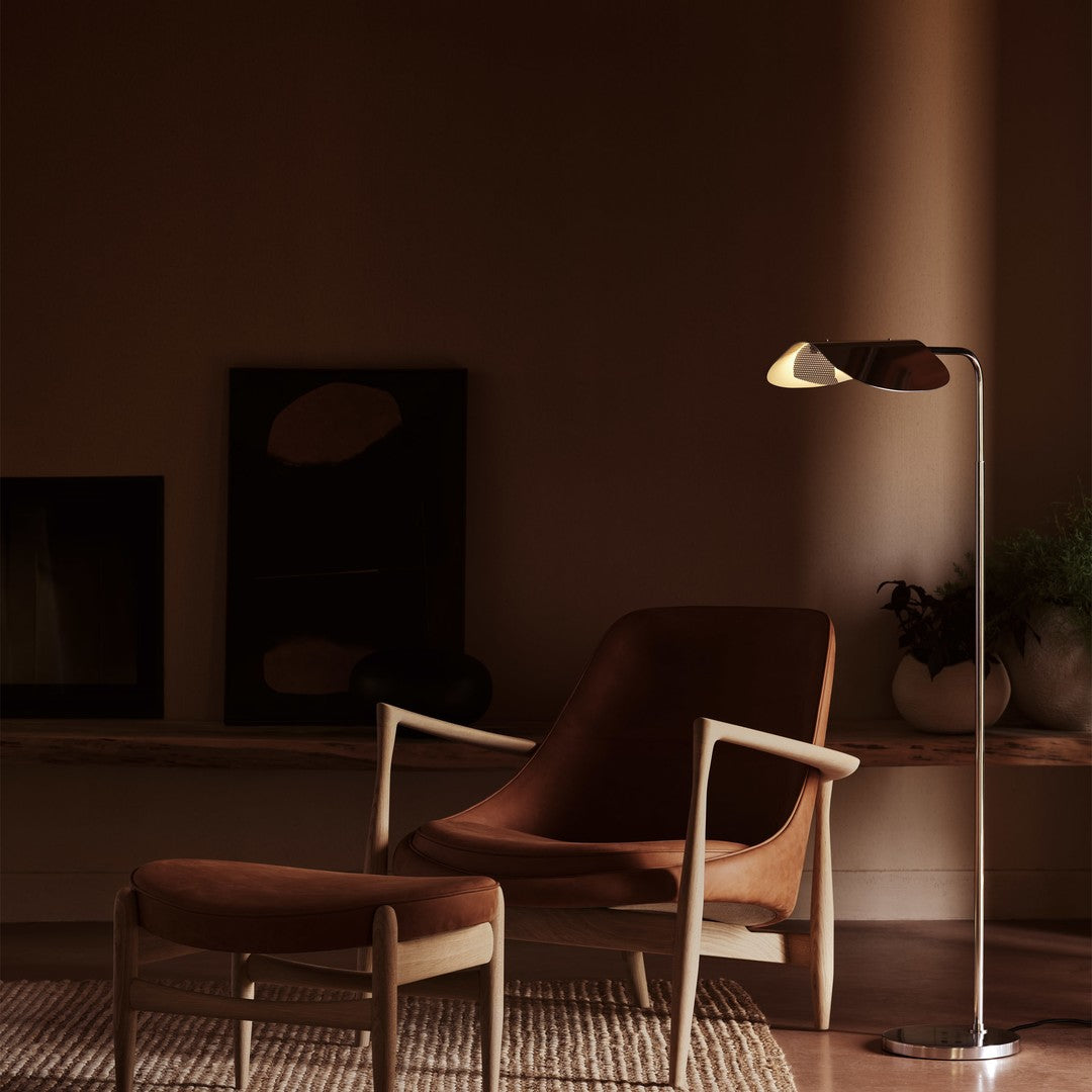Elegant brown chair and ottoman with a sleek metallic floor lamp, set against a warm, muted backdrop.