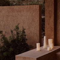Neutral-toned candle holders in varying heights, showcasing soft matte finishes and warm, ambient colors.