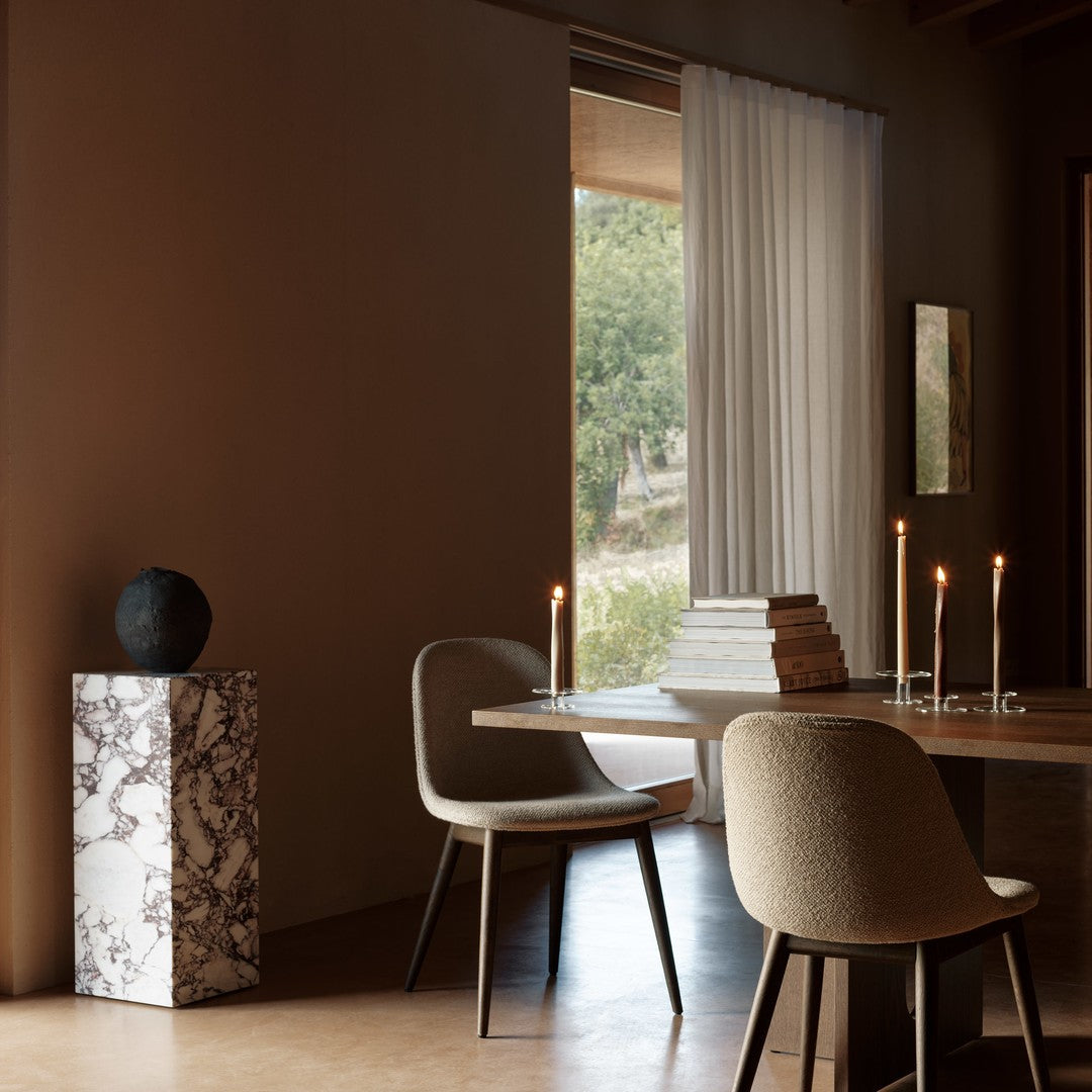 Neutral tones with soft beige chairs, dark accents, and a striking marbled pedestal create a warm, inviting ambiance.
