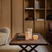 Elegant wooden table with neutral-toned candles and books, featuring warm beige and light brown hues in a cozy setting.