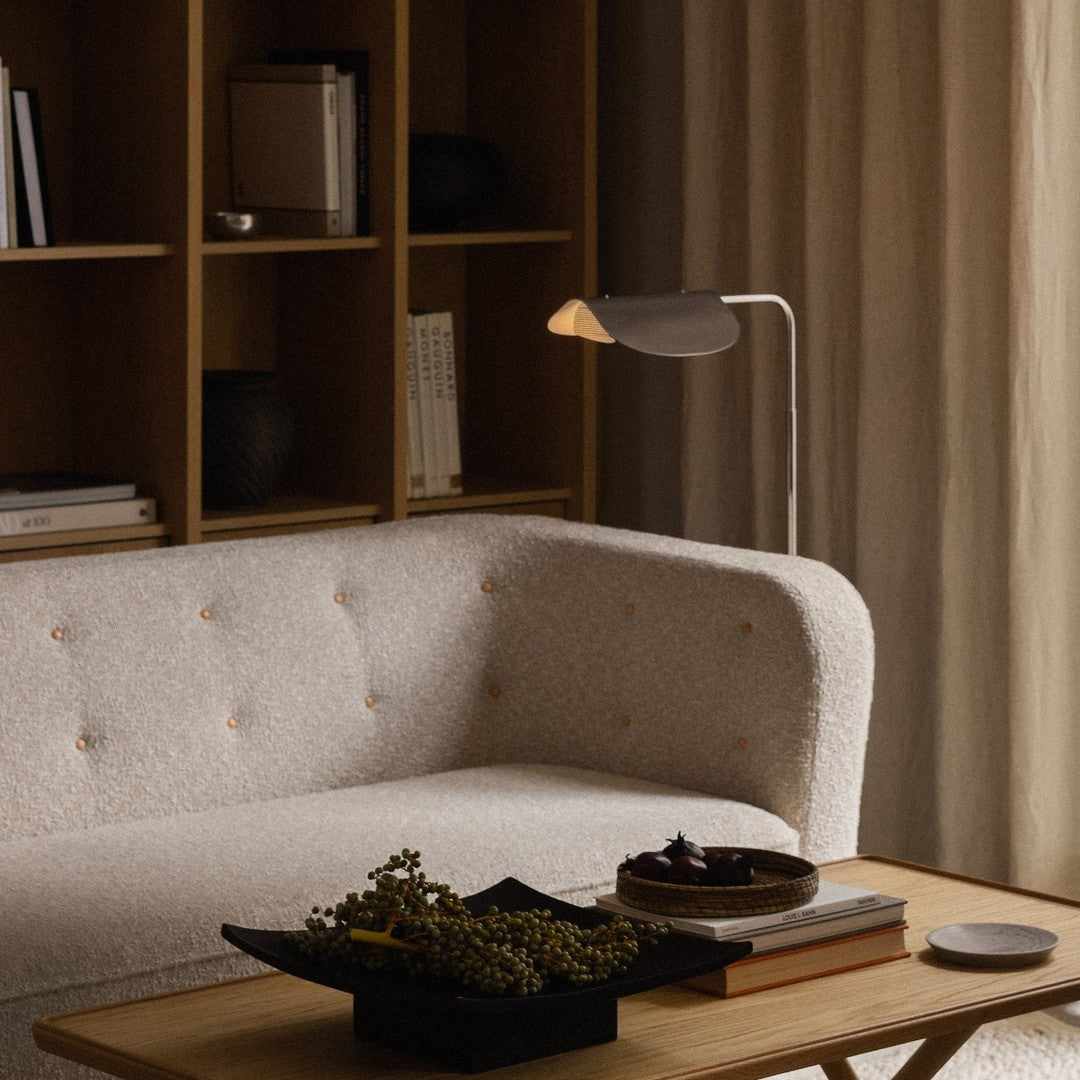 Soft beige sofa with subtle button tufting, complemented by a wooden table and neutral-colored decor elements.