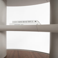 Minimalist design featuring a white background, curved surfaces, and a rich brown wooden shelf.