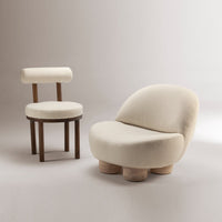Cream textured upholstery with soft curves and minimalist design, complemented by a wooden accent chair.