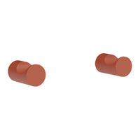 "Pair of round muted terracotta-colored knobs, smooth surface with a contemporary design."