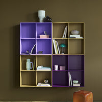 Colorful geometric bookshelf in purple and beige with decorative items against a brown wall.