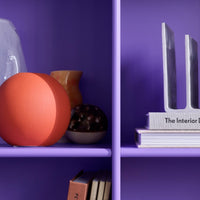 "Colorful display of orange and purple decor items with varied patterns on a vibrant purple shelf."
