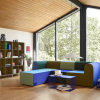 Multicolored modern sofa in blue, green, and purple with sleek lines against a bright, natural backdrop.