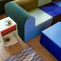 Colorful modular couch in green, blue, and purple. Includes a patterned rug in muted tones with a stylish side table.