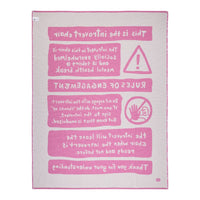 Light gray fabric with bold pink text and warning symbols, featuring a contemporary graphic design.