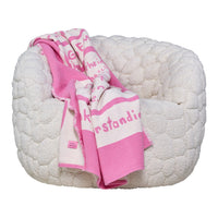 Cozy white plush pet bed with a pink patterned blanket draped over it, featuring soft textures and vibrant colors.
