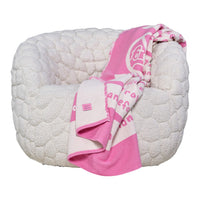Cozy white textured chair with a soft pink patterned blanket draped over the side.