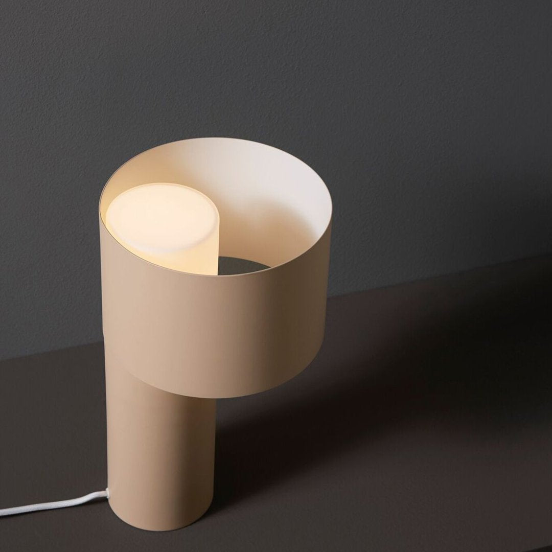 Modern beige lamp with a circular, layered design and soft white light against a dark background.