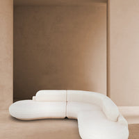 Curved white sectional sofa against a smooth beige wall, showcasing minimalist design and neutral tones.