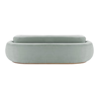 Soft green velvet ottoman with smooth, rounded edges and minimalist design. Perfect for modern decor.