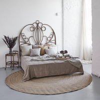Light beige bedspread with textured patterns, surrounded by neutral pillows and a natural fiber rug in a soft setting.