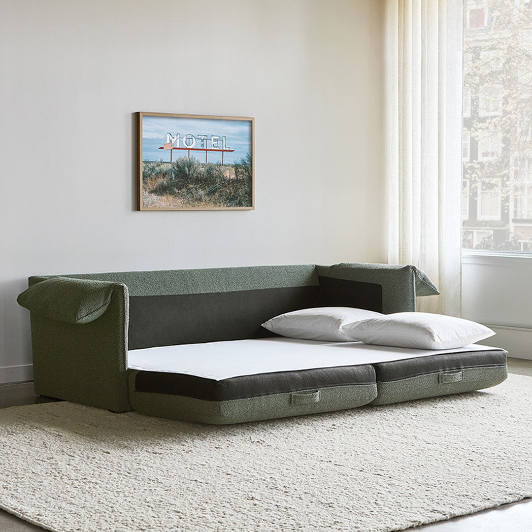 "Stylish sofa in olive green fabric with contrasting dark grey cushions, minimalist design, and modern aesthetic."