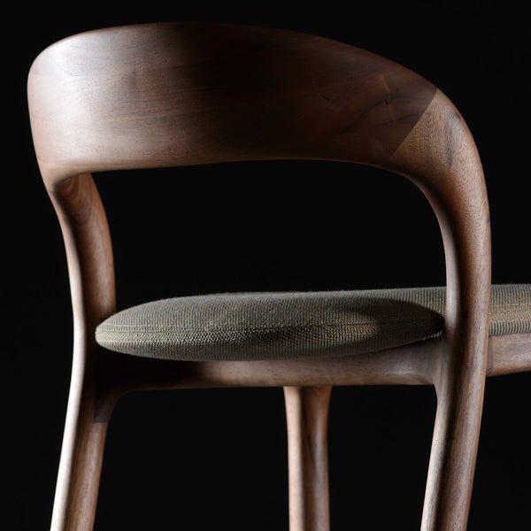 Dark wooden chair with a smooth finish and a beige woven seat, set against a black background.